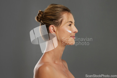 Image of Beauty, face and skin with a woman using antiaging cream in studio on a gray background with mockup. Skincare, treatment and body care with a beautiful female advertising healthcare from the side