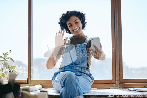 Image of Phone, selfie or video call with a woman on social media while sitting on a table by a window inside with a wave. Communication, networking and internet with a young female using wifi technology