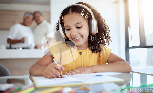 Image of Girl, homework and music while drawing in book for school, assignment or fun in family home. Child, education and notebook for learning with headphones for audio, radio or streaming in house at desk