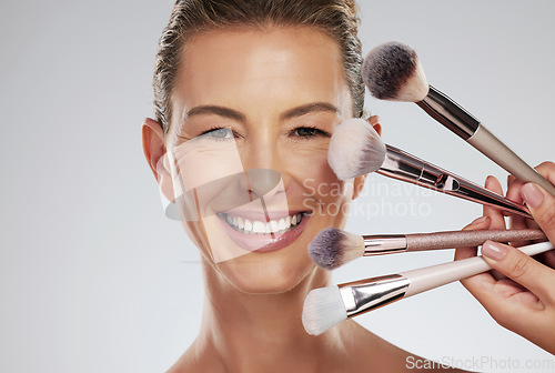 Image of Makeup, beauty and woman with foundation brushes in studio portrait with facial cosmetics and skincare products. Smile, and happy make up artist or beautician and elegant face model with mockup space