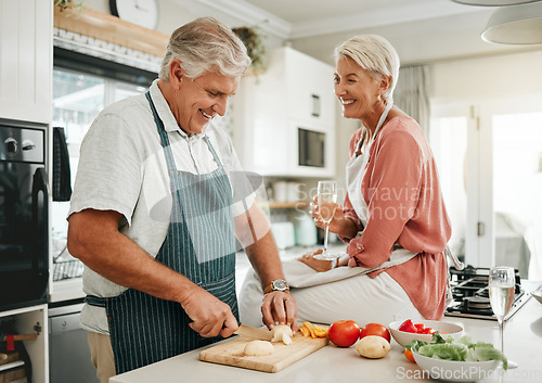 Image of A happy senior couple, cooking healthy food in kitchen and drinking champaign as they enjoy retirement. Elderly woman with sitting on counter, man with silver laughing and they smile in love together