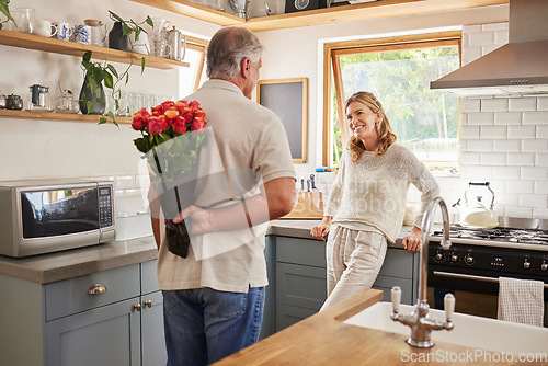 Image of Senior, couple and flowers for love in kitchen, husband with bouquet of roses to wow wife, happy and marriage on wedding anniversary. Man, flowers and woman together, romance and surprise in home