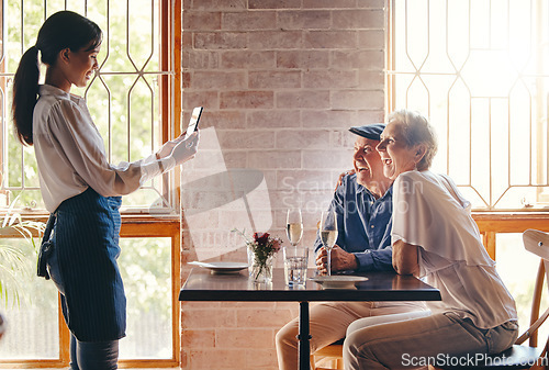 Image of Photograph, restaurant and date with a senior couple in celebration of an anniversary and waitress using a phone. Service, romance and travel with a man and woman tourist posing for a picture