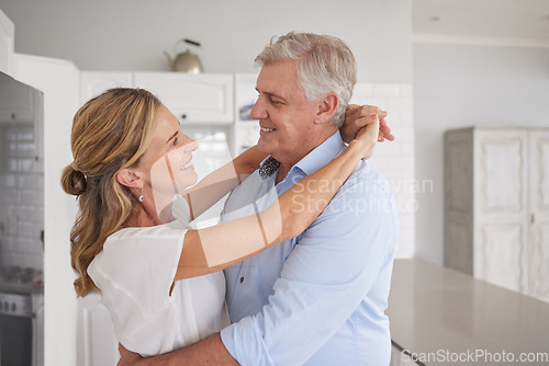 Image of Happy senior couple, love and hug for care in joyful relationship together in the kitchen at home. Elderly man and woman smile, dancing and sharing a bonding moment of romance at the house