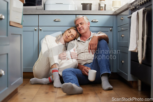 Image of Senior couple, love and support while sitting together feeling safe, relax and calm drinking coffee and bonding comfortable on a kitchen floor. Happy old man and woman enjoying retirement together