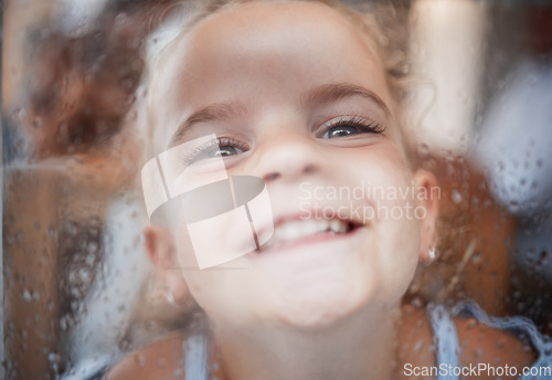 Image of Happy funny girl, face on window with flat nose on rainy glass and comic portrait at home. Young kid play joke, child alone with big smile and laughing crazy humor closeup in San Francisco winter