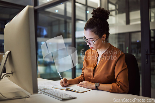 Image of Woman, night office writing and computer planning for business ideas, schedule and strategy in startup company. Focus employee, notebook schedule and desktop information for report in dark workplace