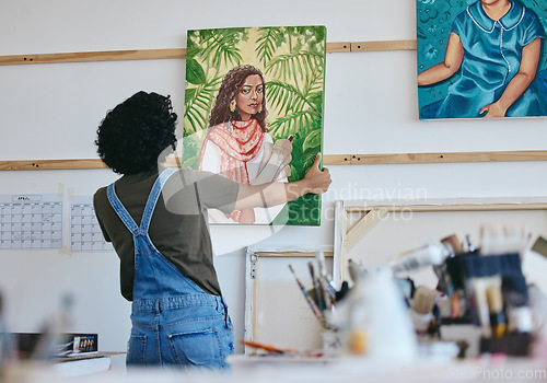 Image of Woman artist, painter and hanging canvas on wall for exhibition to display in studio, art gallery or workshop. Female, lady and creative showing and holding artistic piece and painting in workspace.