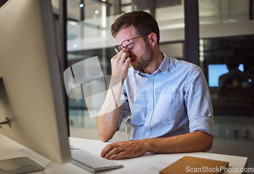 Image of Night business, stress and tired man sitting at his computer desk with headache, depression and burnout from work pressure. Stressed, mental health and depressed male working late in his office