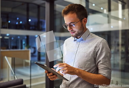 Image of Man in office, working on tablet at night in the office and testing campaign strategy for marketing company. Dedicated professional employee, working late on project and using technology at business