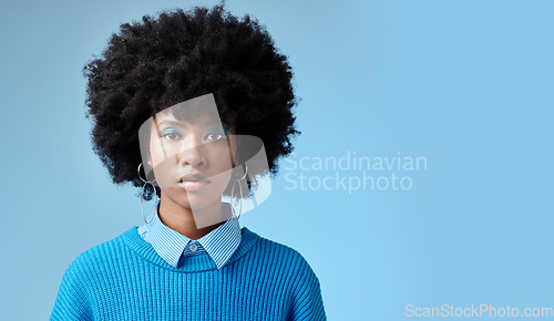 Image of Portrait of black woman, fashion afro and serious face with an expression of focus on blue background studio mockup. Trendy earing accessory, stylish cool clothing and blue cosmetic eyeshadow makeup