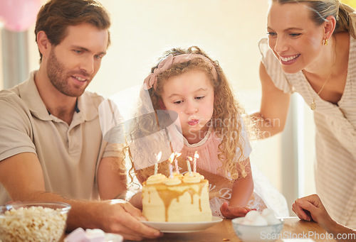 Image of Birthday, candles and family celebration with cake, parents and girl for a happy family event. Happiness, love and smile of a mother, father and young daughter together blowing a candle in a home