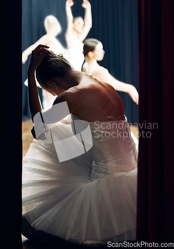 Image of Dancer thinking backstage at ballet concert or recital while group on theater stage. Girl ballerina waiting on floor of auditorium, anxiety and nerves, for performance in front of audience or crowd