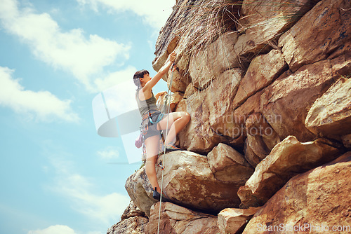 Image of A woman in nature rock climbing, training and fitness outdoors on a sunny day with climbing equipment. A female, strong and healthy athlete doing exercise, physical activity and extreme climbing.