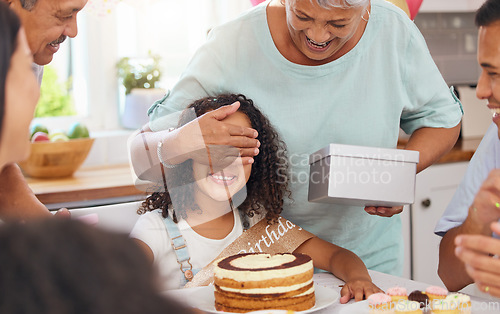 Image of Child, birthday present and celebration party with grandma covering eyes for gift box surprise from family at home. Cute kid at a table in Puerto Rico house celebrating with cake and snacks on table
