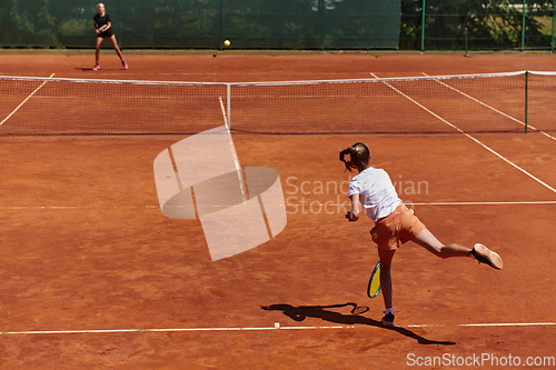 Image of Young girls in a lively tennis match on a sunny day, demonstrating their skills and enthusiasm on a modern tennis court.