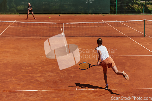 Image of Young girls in a lively tennis match on a sunny day, demonstrating their skills and enthusiasm on a modern tennis court.