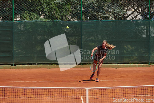 Image of A young girl showing professional tennis skills in a competitive match on a sunny day, surrounded by the modern aesthetics of a tennis court.