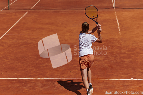 Image of A young girl showing professional tennis skills in a competitive match on a sunny day, surrounded by the modern aesthetics of a tennis court.