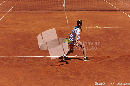 Image of A young girl showing professional tennis skills in a competitive match on a sunny day, surrounded by the modern aesthetics of a tennis court.