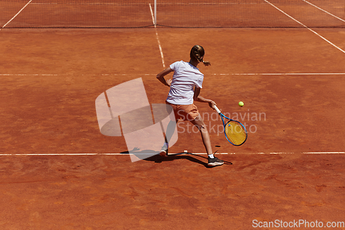 Image of A young girl showing professional tennis skills in a competitive match on a sunny day, surrounded by the modern aesthetics of a tennis court.