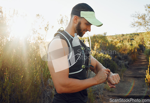 Image of Man, nature and hiking with time on smartwatch in sunshine for run, hike or race. Runner, fitness and trail for health, wellness and workout on sport adventure during summer with tech, gps or clock