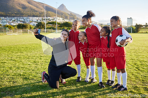 Image of Soccer, team and coach selfie with phone on a field after training, practice or game at a sports club. Football girl group smile and happy with photo for social media on a sport ground together