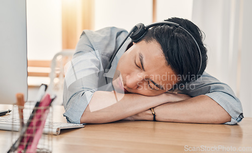 Image of Man, burnout and tired at work in call center, communication or customer support job in Shanghai. Asian, worker and crm sleeping in office at customer service, consulting or telemarketing in China