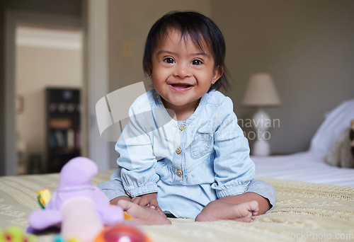 Image of Happy baby with down syndrome, portrait on bed with smile of Mexican kid with special needs relaxed in home. Happy toddler girl in Mexico with disability and cheerful joy sitting in bedroom.