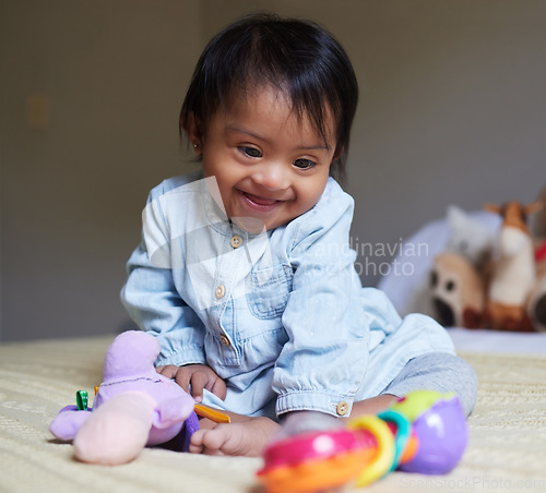 Image of Happy, smile and baby with down syndrome playing with toys for child development in a bedroom. Happiness, learning and girl child with disability or special needs having play time on a bed at home.
