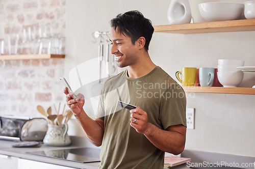 Image of Credit card, finance and man with smartphone for online shopping in kitchen at home. Indian, make payment with money for e commerce transaction and search the internet for investment.