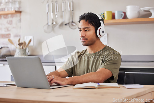 Image of Laptop, kitchen and student with music headphones to listen to rock song while working on research project. Young gen z man relax at home while streaming audio podcast or radio for peace and wellness