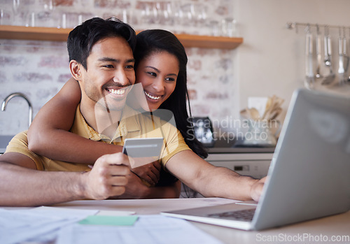 Image of Laptop, credit card and finance with an accounting couple using a computer for ecommerce in the kitchen of their home. Money, savings and investment with a man and woman making an internet purchase