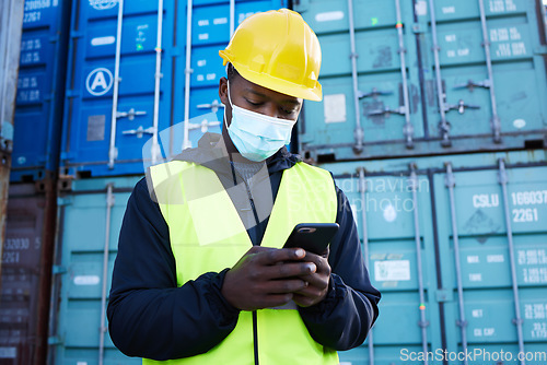 Image of Mask, covid and logistics and black man with phone or shipping worker check a online order on a container port. Stock, freight and cargo with a male courier at work in export and delivery industry