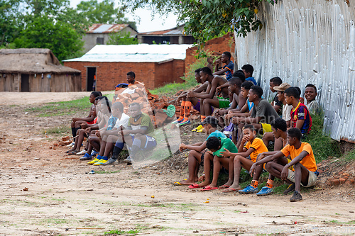 Image of Soccer fans sitting on the ground and watching a local match between two teams from the village. Bekopaka Madagascar