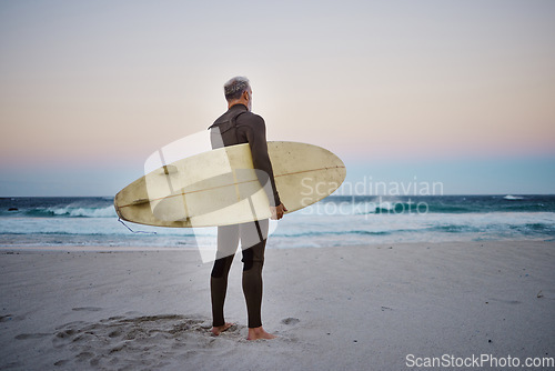 Image of Surfer, surfboard and senior man on beach at sea waves in during sunset during summer vacation in Hawaii. Professional male athlete rest after training or practice surfing sport outdoor at the ocean
