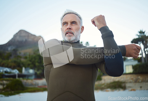 Image of Fitness, surf and stretching with a sports man getting ready for a workout, exercise or training outdoor at the beach. Health, wellness and performance with a mature male at the start of his routine