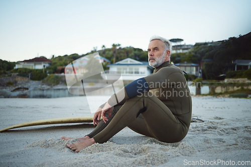 Image of Thinking, relax and surfer man on the beach for rest, peace and freedom while on tropical holiday. Thoughtful, retirement and senior man sitting on sand in nature by the ocean during surf training.