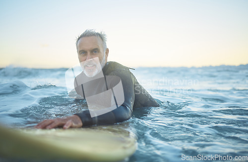 Image of Senior man, surfing in the ocean of Indonesia and free to travel the world in retirement life. Retired surfer, swimming in the sea for fitness and exercise looking to catch a perfect wave on holiday