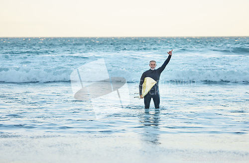 Image of Shaka, surf and sports with a mature man doing a hand gesture in the beach water during summer. Surfer, sea and nature with a male athlete in the ocean for workout, fitness or exercise in a wetsuit