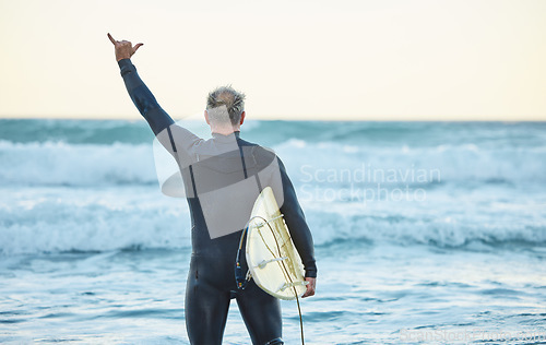 Image of Beach, freedom and man surfing on holiday by the sea in Australia for travel and adventure during summer. Back of surfer with shaka hand sign for free vacation by the ocean and water in nature