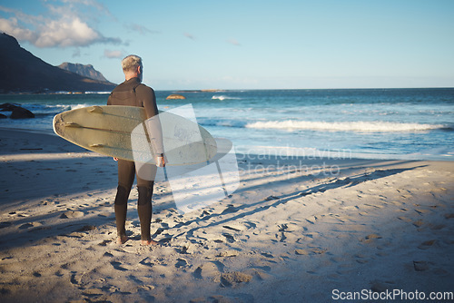 Image of Surfer, elderly and beach for wellness, fitness and health to surf on adventure in summer. Senior, man and sea in morning with waves by ocean to relax, workout and exercise in water in Australia