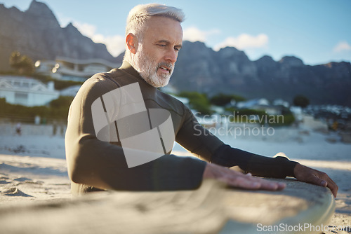 Image of Surf, sand and sports with a man on the beach for surfing, training or exercise on a summer day. Fitness, workout and travel with a mature surfer cleaning a surfboard while on retirement vacation