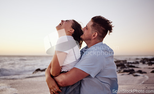 Image of Sunset, love and young couple on the beach bonding, laughing and enjoying their honeymoon holiday. Happy, fun and man embracing and playing with woman while on romantic vacation in Miami Florida.