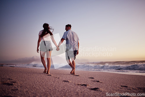 Image of Love, holding hands and couple walking on the beach relax, bond and enjoy romantic quality time together in Israel. Peace, freedom and ocean air for man and woman on sea sand travel for wellness calm