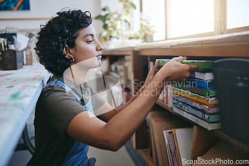 Image of Creative, woman and art collection on shelf preparation and organisation of professional artwork. Artistic Indian person busy with storage strategy and sale planning of paintings in workshop.