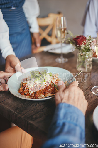 Image of Food, restaurant and hands with a couple and waitress serving a pasta in a fine dining establishment. Date, romance and together with a senior man and woman enjoying eating on their anniversary