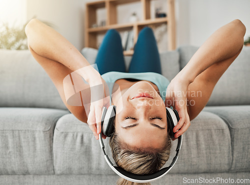 Image of Relax, music and freedom with a woman listening to audio on headphones while lying on a sofa in the living room of her home. Wellness, mental health and streaming with a young female alone in a house