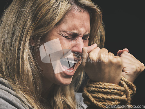 Image of Danger, scared and horror woman scream for help with hands tie and trapped by rope on black studio background. Violence, sad or anxiety female with crime, fear and prisoner, crying for mental health