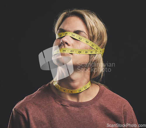 Image of Face, tape measure and stress with an anorexia woman in studio on a dark background for mental health and eating disorder. Sick, hunger and weight with a female struggling with society body pressure